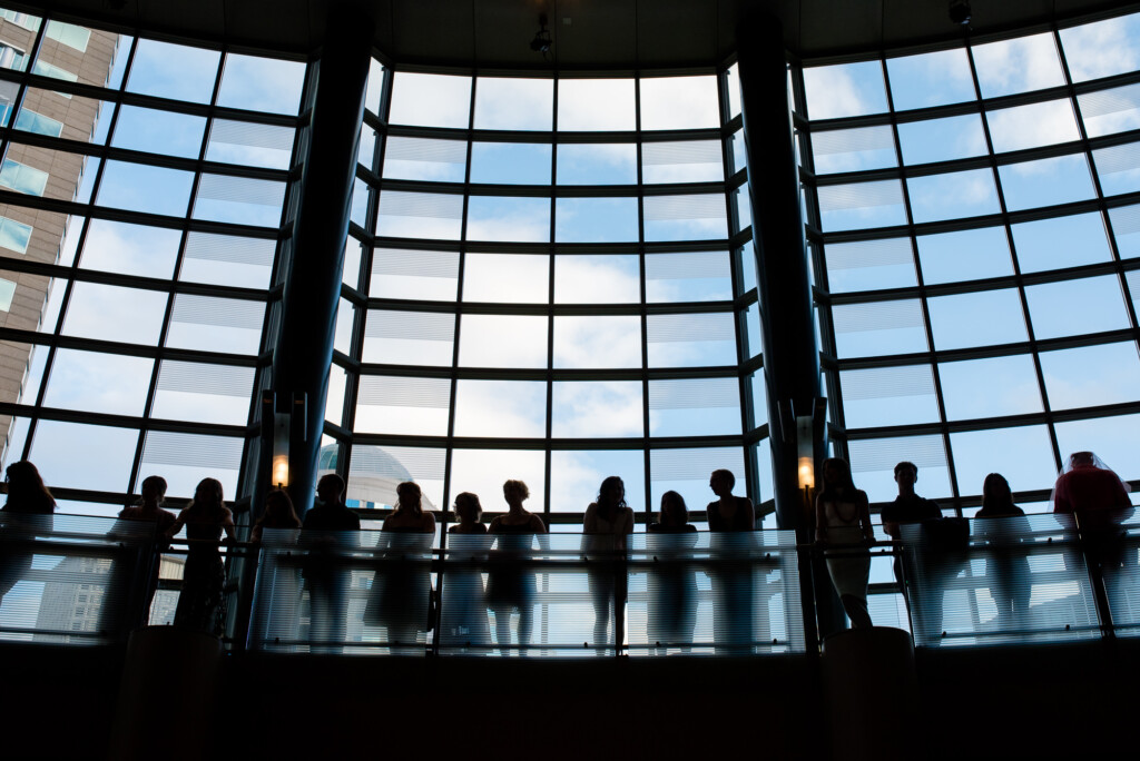 Picture of seniors on an upper level silhouetted in front of a large window at Cornish College Commencement at McCaw Hall